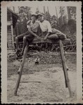 Bezalel Charney (left) sits with a friend on a wooded frame in a Jewish farm in Eisiskes.