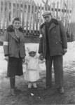 Portrait of a couple with their young daughter on the street in the Rymanow ghetto.