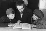 A teacher reviews a religious text with two boys in the Landsberg displaced persons' camp.