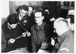 UNRRA camp director Harold Fishbein (lower right) and other personnel view photographs in an office in the Schlachtensee displaced persons camp.