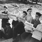 Jewish DP youth who numbered among the Buchenwald children, read an assortment of Yiddish newspapers outside on the grounds of an OSE (Oeuvre de Secours aux Enfants) children's home in France [either in Ambloy or Taverny].