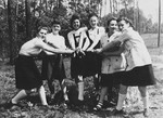 A group of Jewish DP girls from the Schlachtensee displaced persons camp pose outside with their hands joined during a Shavuot holiday outing.