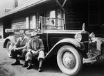 Two Austrian men pose next to a brand new, large automobile which they purchased for use as a taxicab.