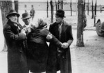 An elderly Jewish woman from Subcarpathian Rus is being held in place by three Jewish men [after having been separated from family members during the selection].