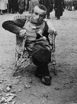A Jewish dwarf who arrived on a transport from Subcarpathian Rus, is seated in a wicker chair on the ramp in Auschwitz-Birkenau.