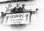 Henia Zoltak (left) and two friends stand on the balcony of her home above a sign advertising the family store.