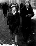Two Jewish siblings walk along a street in Krakow.