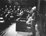Hermann Goering sits in the witness stand with American Military policemen on either side during the International Military Tribunal in Nuremberg.
