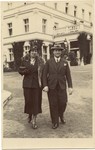 A German Jewish couple walks on the grounds of a large building.
