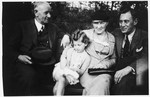 Three generations of a German-Jewish family pose together on a park bench.