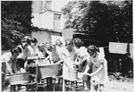 Women and girls do the laundry outside in metal tubs at the Orphelinat Israelite de Bruxelles children's home on the rue des Patriotes.