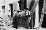 An Italian instructor, Meletti Fano, demonstrates how to fix fishing nets to four Jewish DPs at the Migdalor hachshara, a maritime Zionist collective in Fano, Italy.
