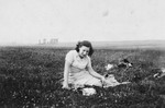 A young woman sits in a field of grass in the Dabrowa Gornicza ghetto.