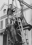 A group of young scientists from the Kaiser Wilhelm Institute pose on the scaffolding outside the institute.