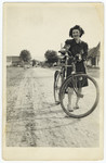 A young Jewish woman stands next to her bicycle on a street in Vonihovo.
