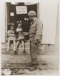 Sgt. Walter P. Goworek gives G.I. candy to two French girls, who are wearing costumes for a Fourth of July observance in La Mine.