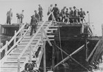 Reichsfuehrer SS Heinrich Himmler stands alongside Max Faust (wearing the fedora) on the upper floor of a partially constructed building, during a tour of the Monowitz-Buna building site.