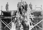 Reichsfuehrer SS Heinrich Himmler (bottom left) descends a wooden staircase during a tour of the Monowitz-Buna building site in the company of Max Faust (bottom right).