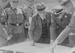 Reichsfuehrer SS Heinrich Himmler examines a building plan with Max Faust (wearing the fedora) during an inspection tour of the Monowitz-Buna building site.