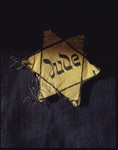A yellow Star of David badge bearing the German word 'Jude' (Jew).