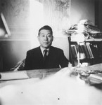 Chiune Sugihara sits behind a desk in his office.