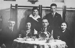 Group portrait of a lithuanian-Jewish family seated around a dinner table.