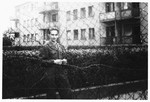 Shmuel Shalkovsky stands by a wire fence in his American army uniform while waiting to escort a group of DPs to America on board the Marine Perch.
