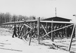 A column of survivors in concentration camp uniform walk through a gate in Buchenwald soon after the liberation.