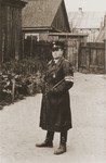 Orenstam, a member of the Jewish ghetto police, stands outside a house in the ghetto.