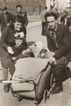 A Jewish DP family poses with a baby carriage on a street in Lodz after the war.