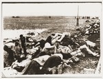 Civilians begin to lay out for burial the bodies of Jews removed from the Iasi death train during a stop on the journey.