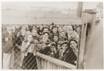 Women and children who have been selected for deportation, are photographed through the wire fence of the central prison, during the "Gehsperre" action in the Lodz ghetto.