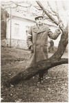 A young Jewish man wearing an armband poses by a tree in the Wisnicz Nowy ghetto.