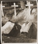 The corpse of a prisoner who died in the concentration camp at Woebbelin lies next to an open grave.