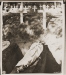 The corpse of a prisoner who died in the concentration camp at Woebbelin lies next to an open grave.