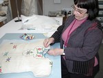 Textile conservator Lizou Fenyvesi repairs a dress worn by a Jewish child while living in hiding in Poland during World War II.