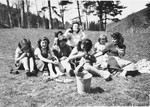 Girls sit on the grounds of La Hille and sew.

Second from left, Irene Kokotek (now Nathan); to her right, possibly Irma Seelenfreund; center rear with hands up, Martha Storosum; far right in dark dress, Gerti Lind.