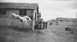 A group of children stands outside a barracks at an internment camp in France, most likely Rivesaltes.