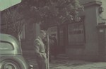 Hans Biebow stands next to an automobile on a street scene in the Lodz ghetto.