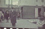An elderly man  carrying a cane poses in the market in the Lodz ghetto.