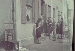 A German official [probably Biebow] talks to Jewish women in the doorway to their home in the Lodz ghetto.