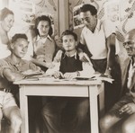 Zionist  youth from the Kladovo transport gather around a table at the movement's headquarters.