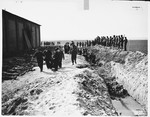 Under the supervision of American soldiers, German civilians remove corpses from a mass grave on the north side of the barn outside of Gardelegen.