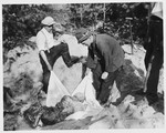 German civilians exhume the corpse of a prisoner from a mass grave for proper reburial.