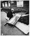 A member of the French resistance examines a blood-stained coffin used by camp personnel to remove bodies from the camp gas chamber.