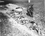American soldiers look at the exhumed bodies of prisoners who were burned alive in a barn outside of Gardelegen.