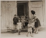 A teacher ushers children through a doorway of a kindergarten in a DP camp in Sankt Marien.