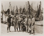Jewish youth living at the Harishona Zionist collective in Fano, pose on a wharf where dozens of fishing boats are moored.
