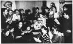 Children in the Foehrenwald displaced persons camp read together during a meeting beneath a portrait of Joseph Trumpeldor.