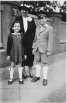 Peter Witting, wearing his school cap, poses on a sidewalk with his mother and sister.